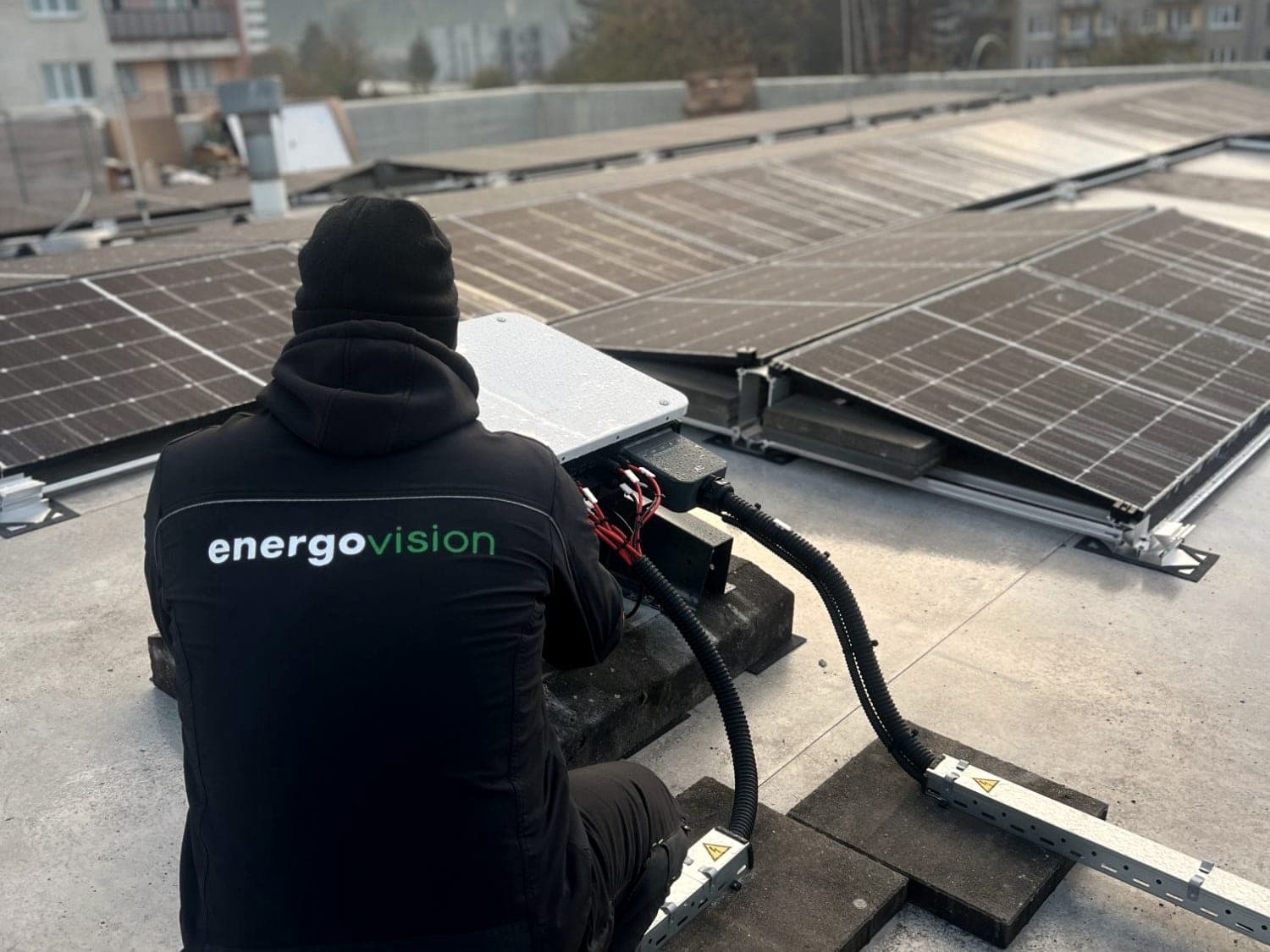 Technik Energovision zapojuje střídač na ploché střeše mezi řadami panelů