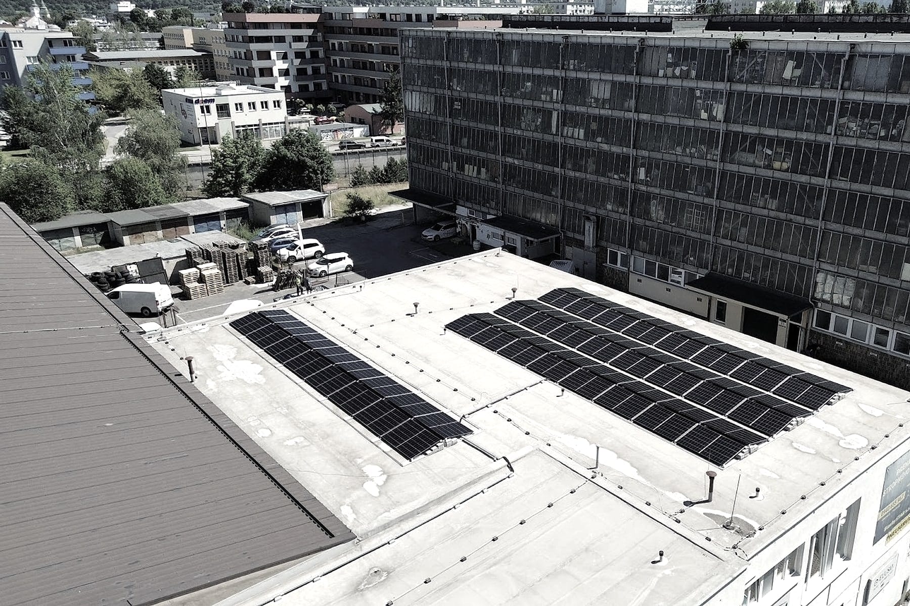 Ortofoto ploché střechy s fotovoltaickou elektrárnou v Žilině, parkoviště a sousední budovy
